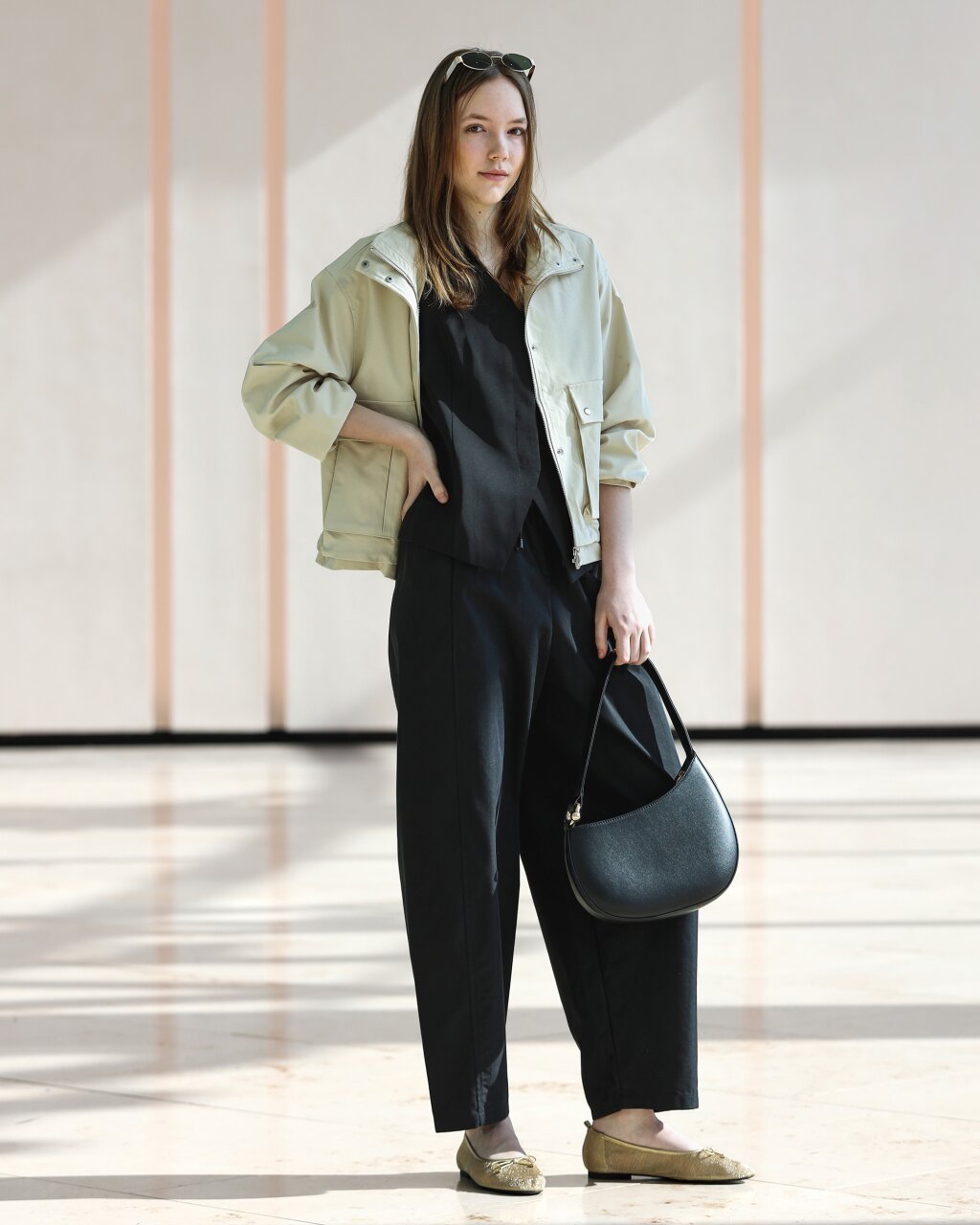 jarn&yacute; žensk&yacute; outfit kombinuj&uacute;ci neutr&aacute;lnu ľahk&uacute; bundičku, čiernu bl&uacute;zku a &scaron;irok&eacute; nohavice.